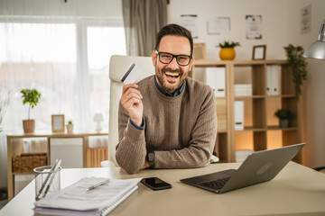 Adult businessman buy online on laptop and hold credit card at office