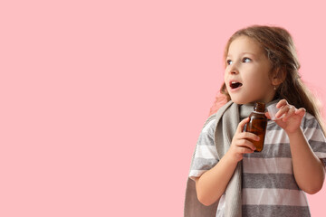 Sick little girl with cough syrup on pink background