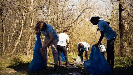 Team of volunteers collecting rubbish to fix pollution problem within the habitat, protect the...