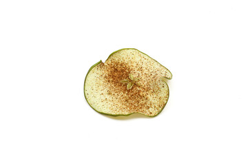 Single slice of dry green apple sprinkled with cinnamon powder isolated on white background. Dehydrated chip snack