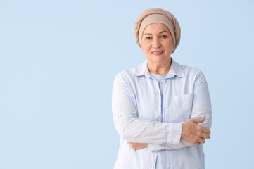 Smiling mature woman after chemotherapy on blue background. Stomach cancer concept