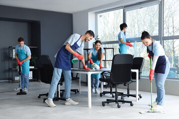 Team of young janitors cleaning in office