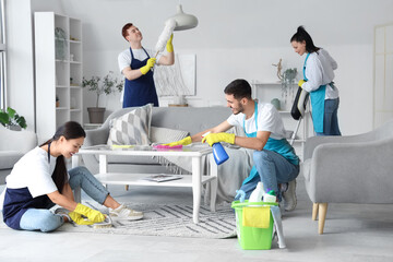 Team of young janitors cleaning in room