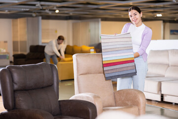 Furniture saleswoman offering material choice in furniture store