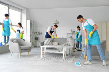 Team of young janitors cleaning in room