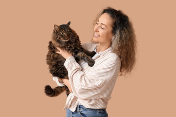 Beautiful mature woman with cute cat on brown background