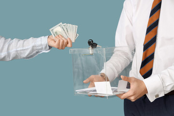 Hand putting money into ballot box on blue background. Election concept