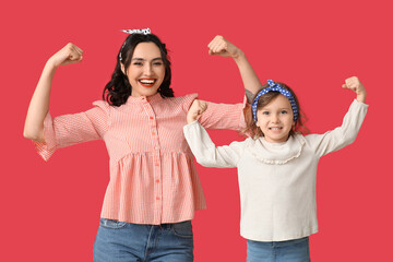 Beautiful pin-up woman and her daughter showing muscles on red background