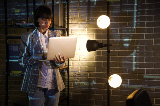 Female programmer working with laptop in office at night