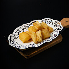 Crispy fried cassava on a plate on a black background