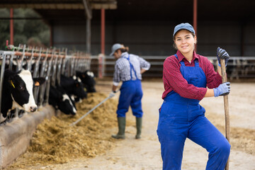 Smiling female farmer posing in cowshed at dairy cow farm