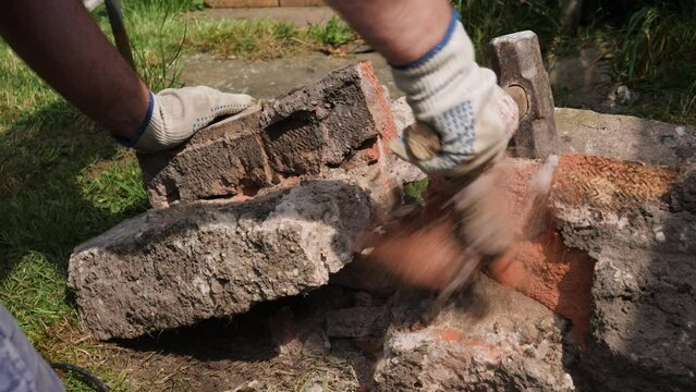 Close up of manual labour construction worker using a lump hammer to break concrete and brick by hand