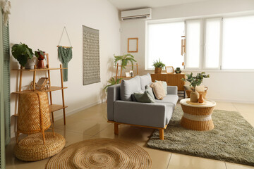 Interior of light living room with wind chime, sofa and plants