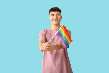 Handsome young happy man with LGBT flag on blue background