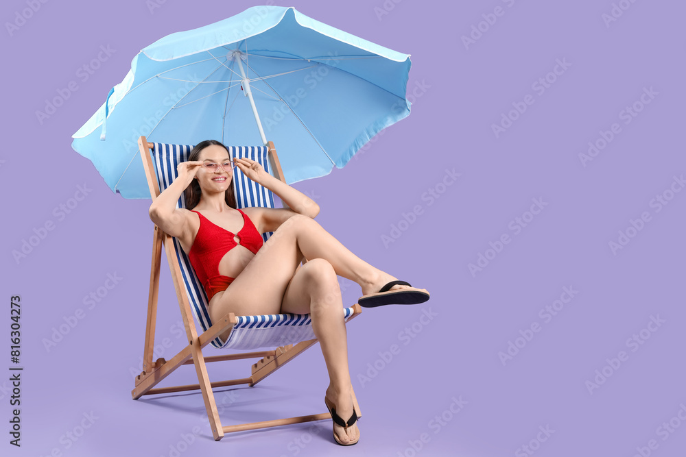 Sticker Woman sitting on deckchair near umbrella against purple background