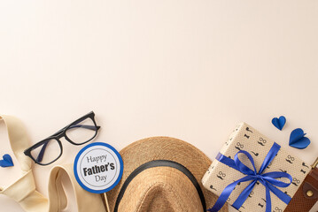 A creative arrangement for Father's Day featuring a straw hat, stylish glasses, a ribbon, a gift box with a blue bow, and a Happy Father's Day sticker on a light beige background