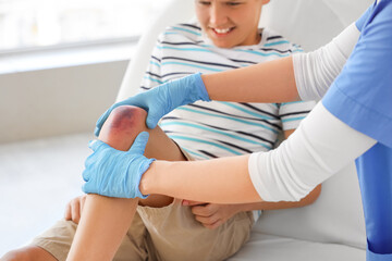 Little boy with bruised knee visiting doctor in clinic, closeup