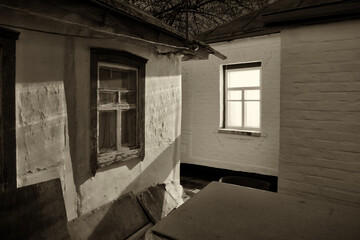 A rural house, night outside, the light from the window brightly illuminates the wall of the neighboring house.