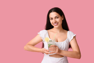Beautiful young happy woman with glass of fresh lemonade on pink background