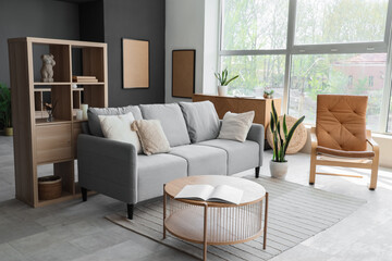 Interior of modern living room with grey sofa, armchair and shelf unit