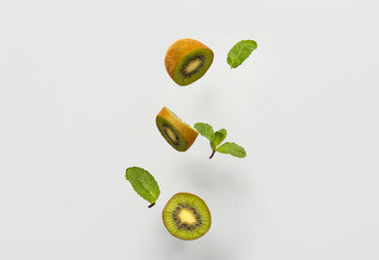 Flying cut kiwi and mint leaves on grey background
