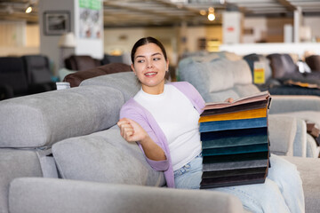 Obraz premium Joyful girl on the sofa infurniture store decides what fabric to choose for furniture