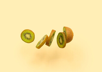 Fresh cut kiwi flying on color background