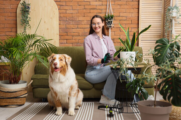 Young woman with cute Australian Shepherd dog and houseplants at home