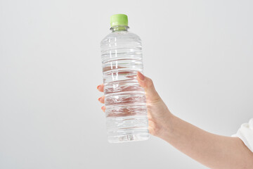 水の入ったペットボトルを持つ女性の手元