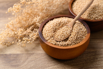 Brown quinoa seed in bowl with spoon on wooden background, Healthy food ingredient