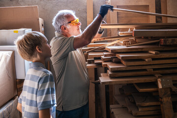 Granddad and grandson work together in the carpenter workshop, selecting and picking the perfect...