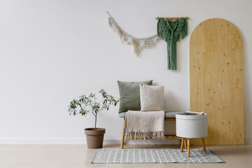 Interior of light living room with soft bench and wall tapestries