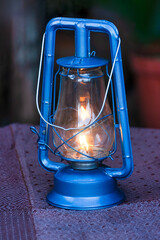 vintage kerosene paraffin lamp , orange flame burning, on blue, background bokeh blur