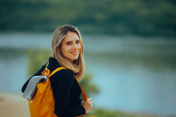 Travel Woman Looking at a Big River Carrying a Backpack. Carefree traveler enjoying natural landscaped with water 
