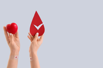 Female blood donor with grip ball and paper drop on light background