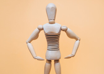 Wooden bodybuilder mannequin shows muscular arms on a beige background. Concept of physical strength and exercise with the gym.