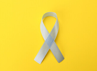 International Psoriasis Day. Ribbon as symbol of support on yellow background, top view