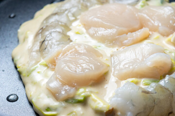 フライパンでお好み焼き(えび・帆立入り)を焼く調理シーン。
