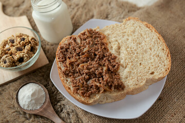 Bread with minced beef and union on a table. With white milk and snack for breakfast	
