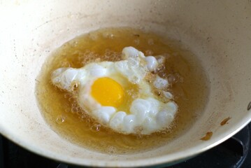 frying an egg on a wok pan