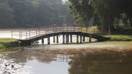 Obraz premium A low concrete bridge connecting two bodies of land at a lake; landscape photography; serene landscape of a bridge with mist or fog early in the morning