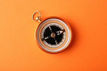 One compass on orange background, top view