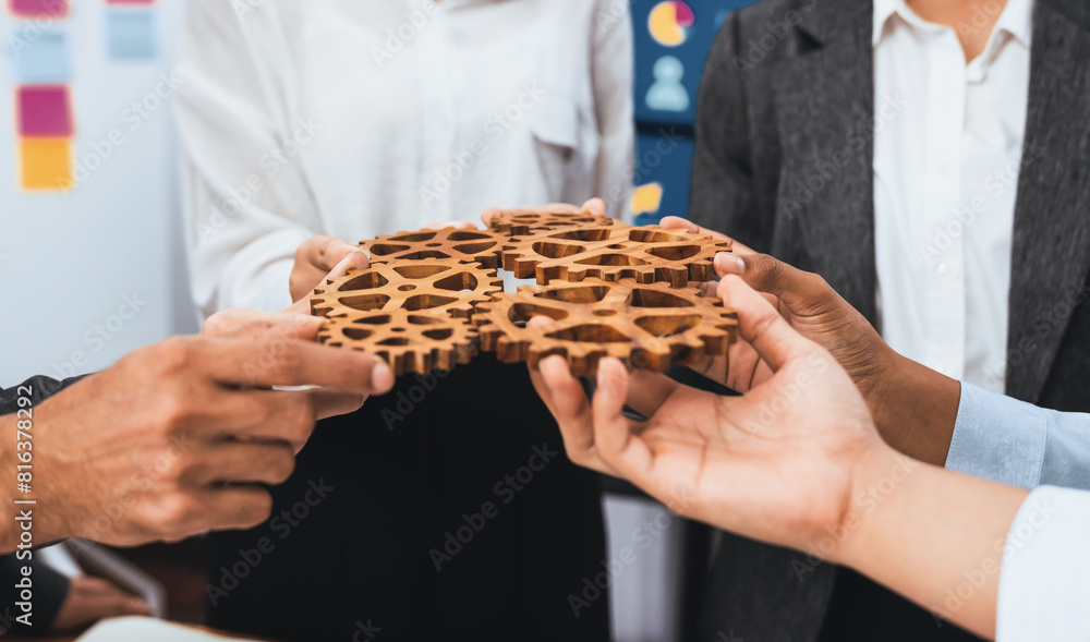 Poster office worker holding cog wheel as unity and system teamwork in corporate workplace with piles of bu