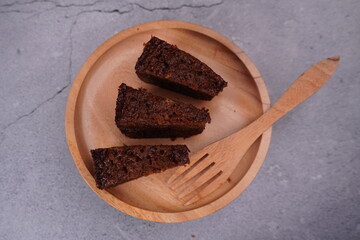 top view chocolate brownie cake in wooden plate with wooden fork