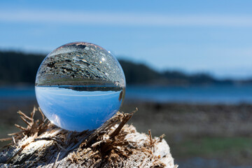 An close up image of a crystal clear photographic lens ball with the Pacific Ocean in the...