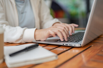 A close-up image of a woman using her laptop computer, typing on the laptop keyboard.