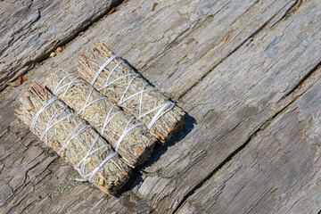 A close up image of three healing smudge sticks on a sun bleached driftwood log. 