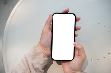 A close-up image of a woman sits outdoors on a sunny day and uses her smartphone.