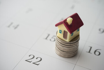 Close up cute house and stack coins on white blank calendar background copy space. Mortgage loan,...