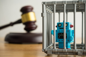 AI artificial intelligence bot in jail and hammer judge gavel on wooden table with white wall...